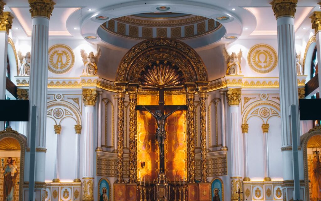 Stunning golden altar with crucifix in an ornate cathedral interior.