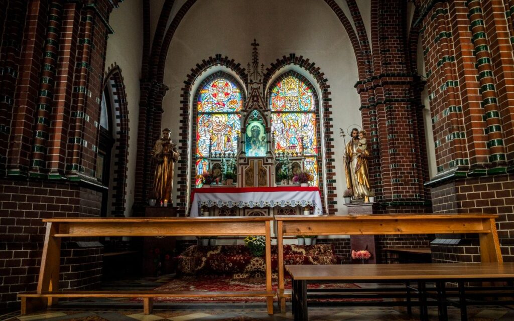 A serene view of a church altar featuring stained glass and statues.