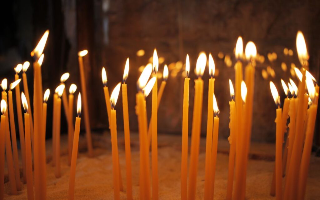 Warm and peaceful image of lit candles inside a church, symbolizing faith and reflection.