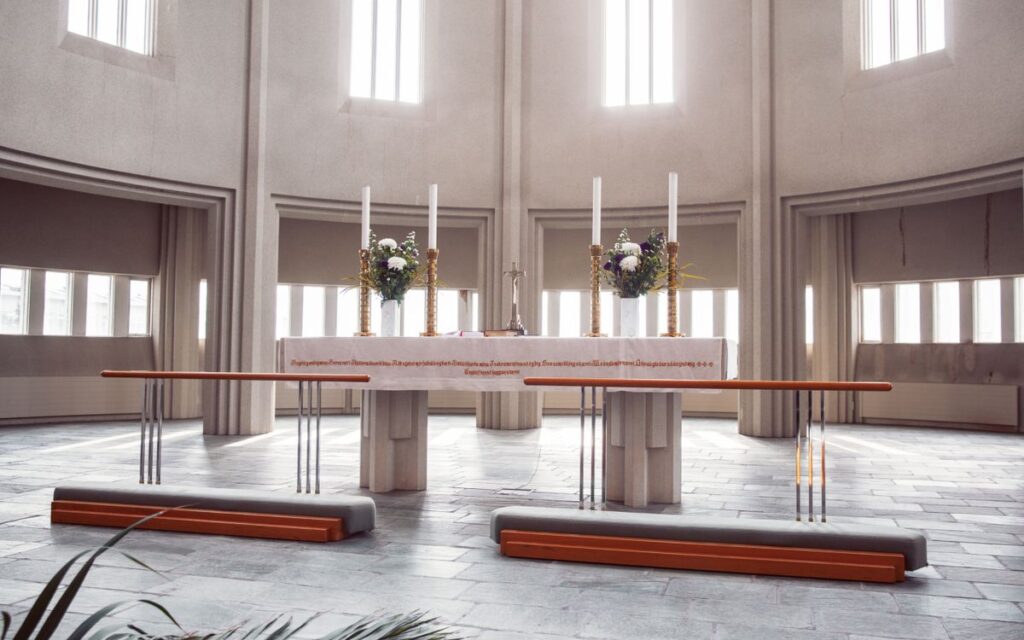 A spacious modern church altar with candles, flowers, and natural light.