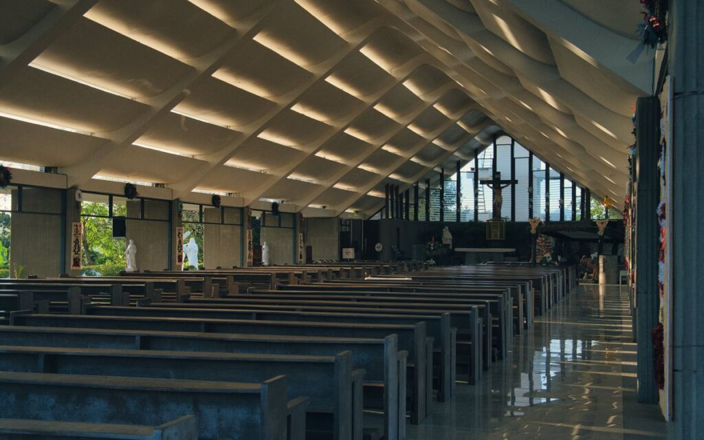Empty modern church interior featuring unique ceiling design and wooden pews, enhancing a peaceful atmosphere.
