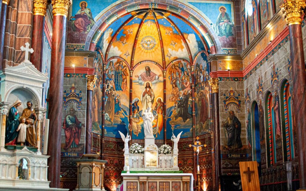 Magnificent church interior featuring a detailed altar with religious paintings and statues.