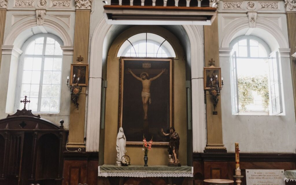 Beautifully detailed church altar featuring statues and a crucifixion painting, capturing sacred ambiance.