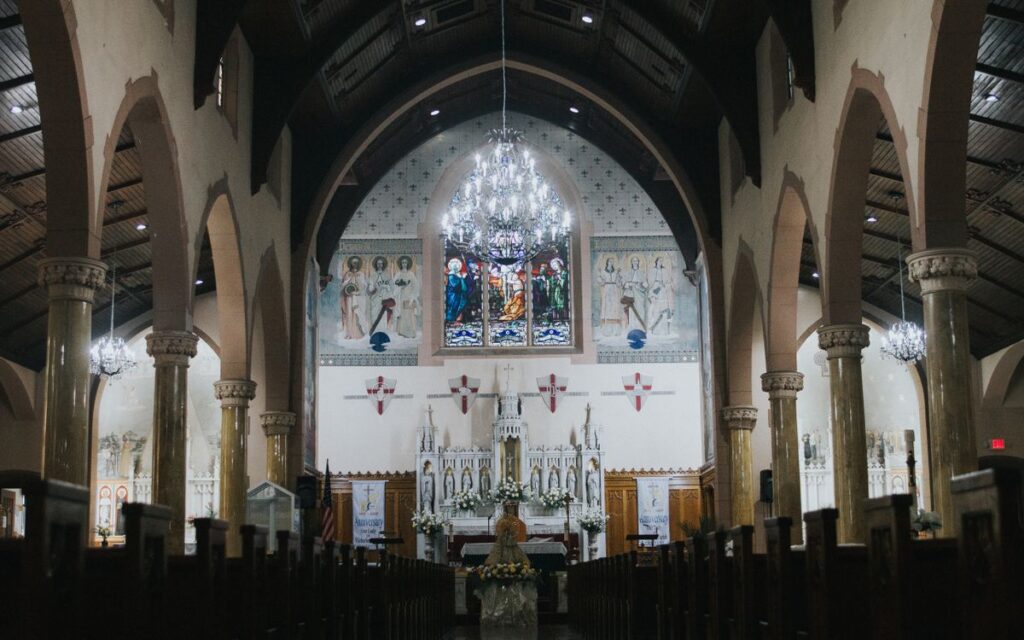 Intricate interior of a historic church with stunning stained glass, arches, and chandeliers.