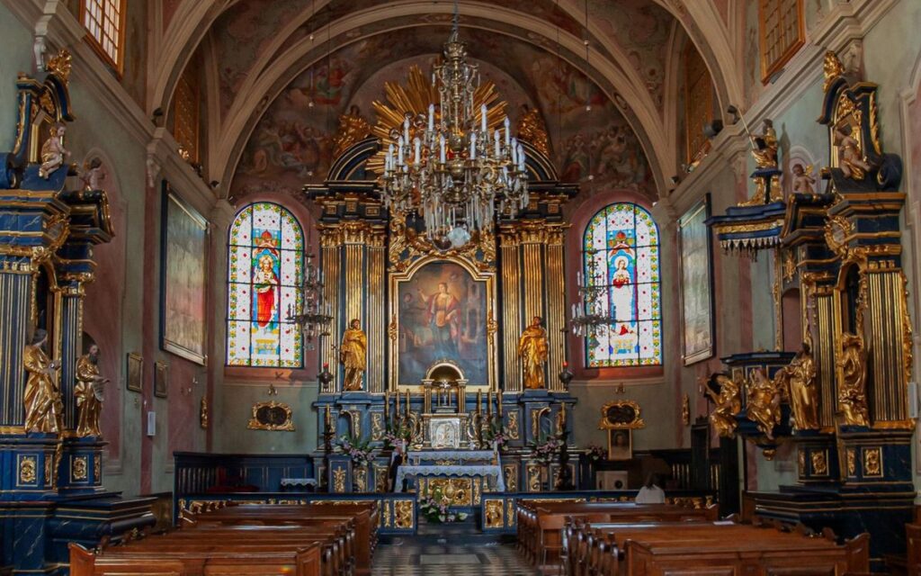 Beautiful ornate altar inside a historic church in Poland, showcasing stained glass windows.