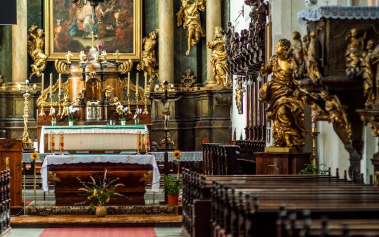 Exquisite baroque church interior featuring a grand altar adorned with gold sculptures and a vibrant painting.
