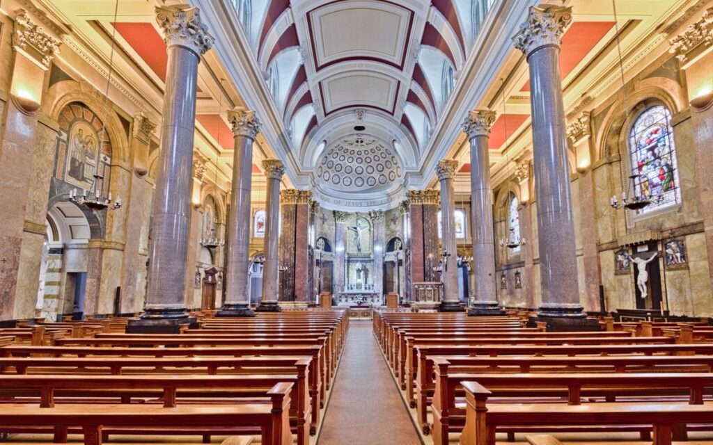 Bright view of a historic church interior in Preston, England, showcasing grand pillars and stained glass windows.
