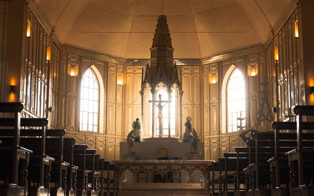 Atmospheric interior of a historic church with ornate altar and statues.