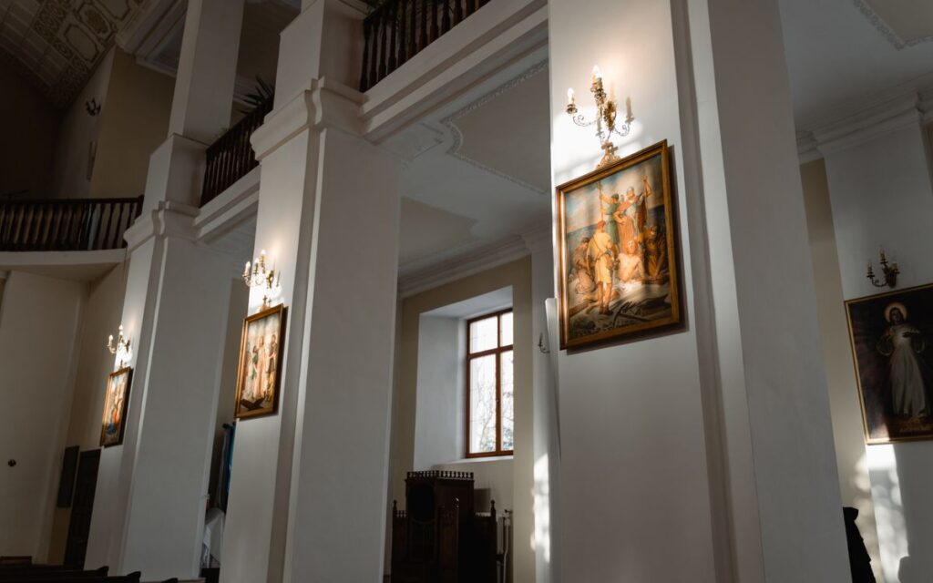 Sunlit interior of a historic church featuring classic religious paintings.